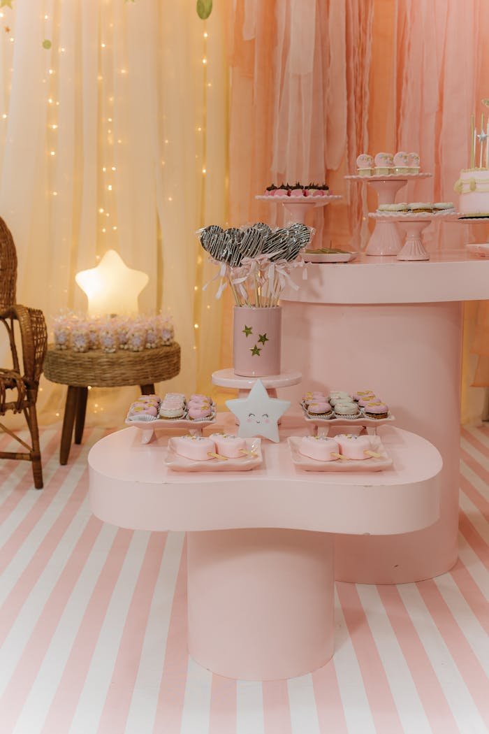 A beautifully decorated pastel pink birthday party setup with sweets and decor elements.