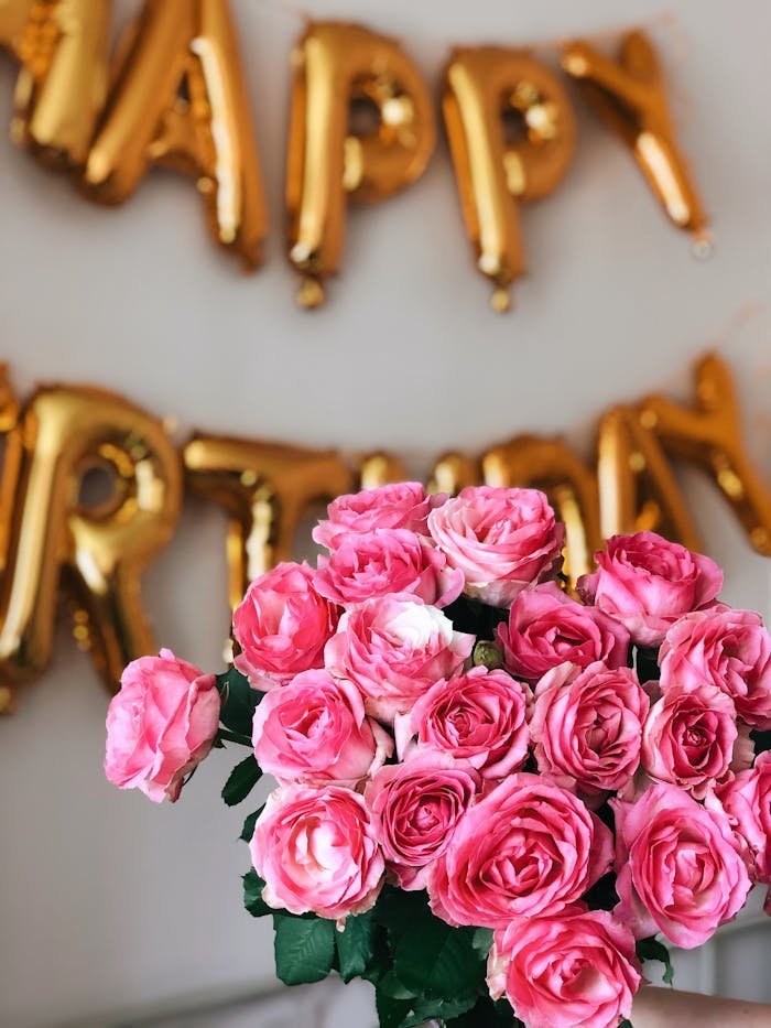 pexels photo 3961916 A stunning bouquet of pink roses at a birthday party with golden balloons spelling 'Happy Birthday' in the background.